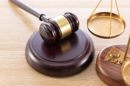 Gavel resting beside stacked books and coins